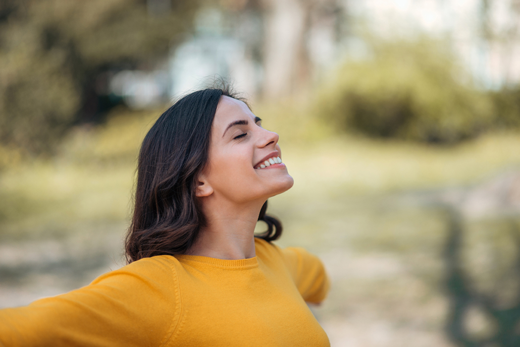 Mujer feliz, con los brazos abiertos, viendo hacia el cielo