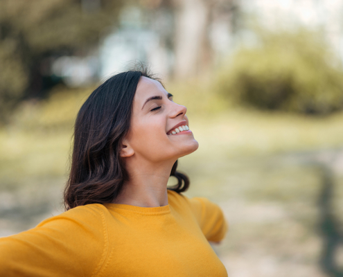 Mujer feliz, con los brazos abiertos, viendo hacia el cielo