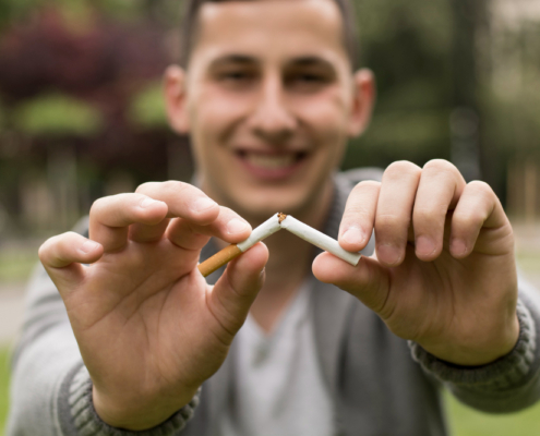 Hombre rompiendo un cigarro, como negándose a fumar